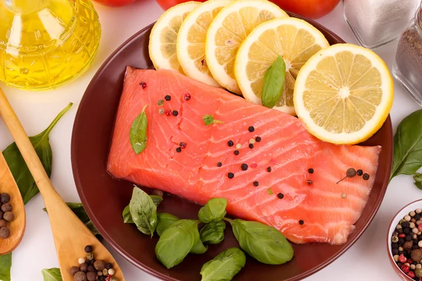 Roter Fisch auf dem Teller mit Paprika und grünen Blättern — Stockfoto