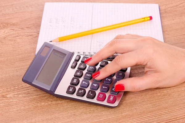 Ręka, notatnik i kalkulator na drewnianym tle — Zdjęcie stockowe
