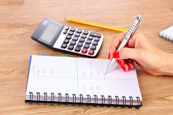 Mão, bloco de notas e calculadora — Fotografia de Stock