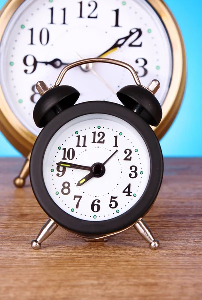 Two clocks with different time on blue background Stock Image