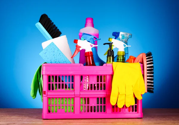 Cleaning supplies in basket on blue background — Stock Photo, Image