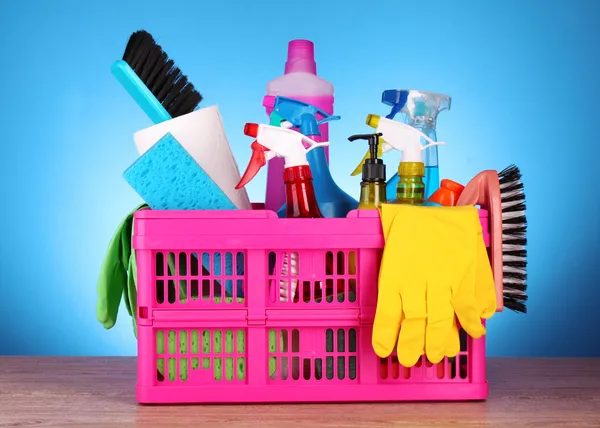 Forniture per la pulizia in cestino su sfondo blu — Foto Stock