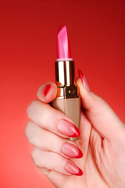 Red lipstick in hand on red background — Stock Photo, Image