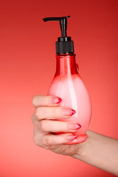 Жидкое мыло в руке на красном фоне — стоковое фото