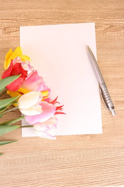 Tulpen en papier op houten tafel — Stockfoto