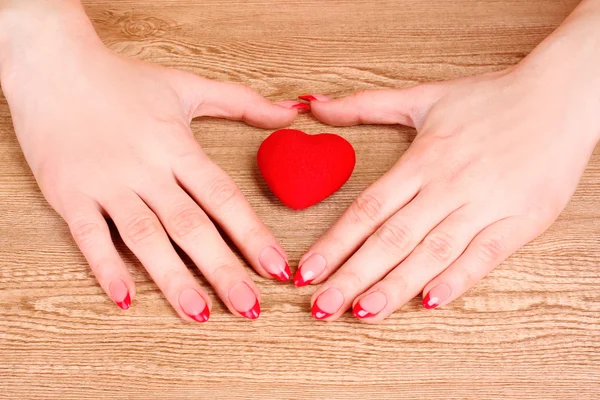 Red heart in hands on wooden background — Stock Photo, Image