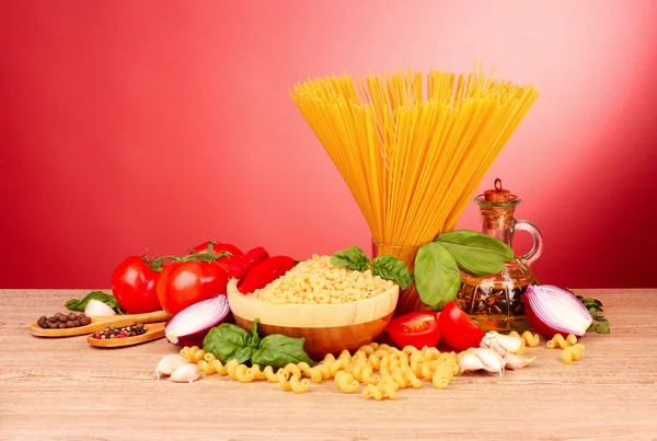 Spaghetti mit Knoblauch, Zwiebeln, Gewürzen und Basilikum auf rotem Backblech — Stockfoto