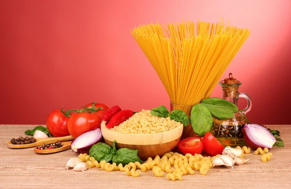 Spaghetti med vitlök, lök, kryddor och basilika på en röd backgro — Stockfoto