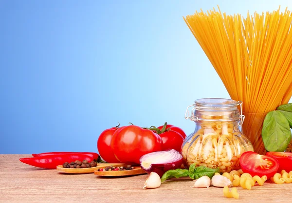 Spaghete cu usturoi, ceapă, condimente și busuioc pe backgrou albastru — Fotografie, imagine de stoc