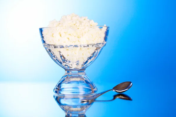 Cottage cheese in bowl on blue background — Stock Photo, Image