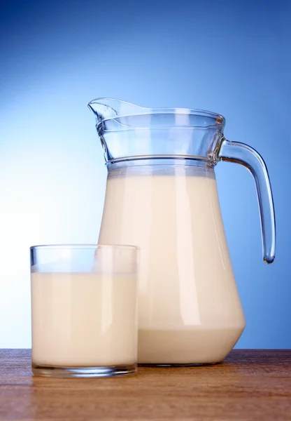 Kancsó és pohár tejjel a kék háttér — Stock Fotó
