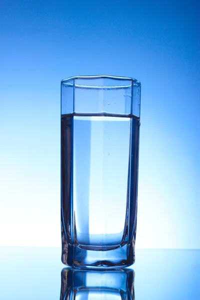 Три окуляри води на синьому фоні — стокове фото