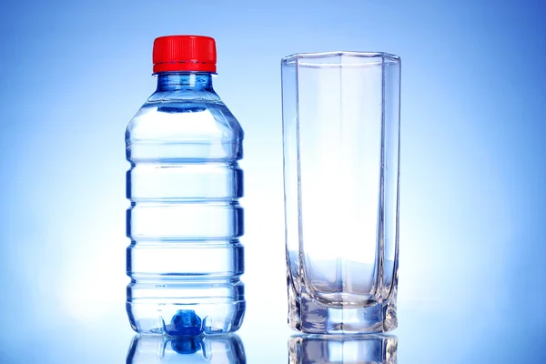 Flasche Wasser und Glas auf blauem Hintergrund — Stockfoto