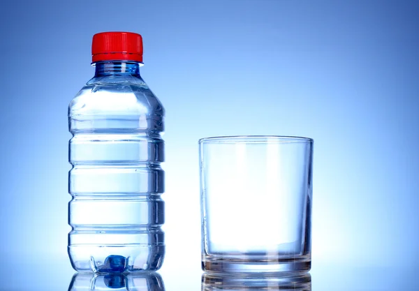 Flasche Wasser und Glas auf blauem Hintergrund — Stockfoto