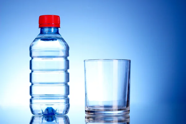 Бутылка воды и стекла на синем фоне — стоковое фото