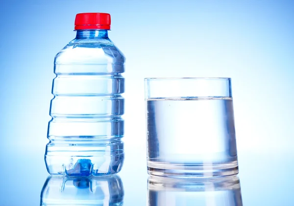 Bottiglia di acqua e vetro su sfondo blu — Foto Stock