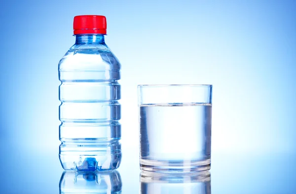 Flaska vatten och glas på blå bakgrund — Stockfoto