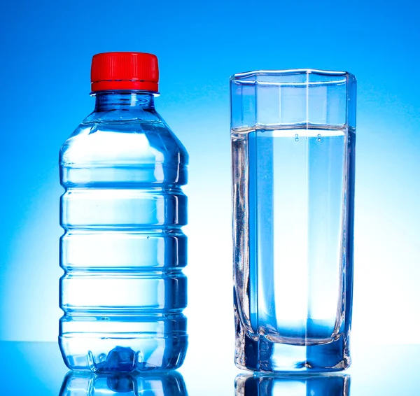 Garrafa de água e vidro sobre fundo azul — Fotografia de Stock