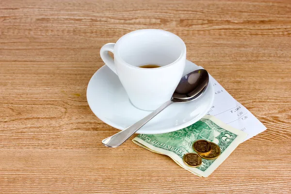 Lege kopje koffie met vijf dollar tip op houten achtergrond. — Stockfoto
