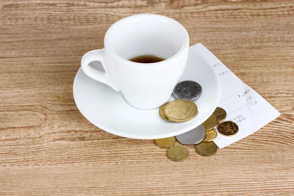 Xícara vazia de café com ponta de moedas em fundo de madeira. Ucrânia — Fotografia de Stock