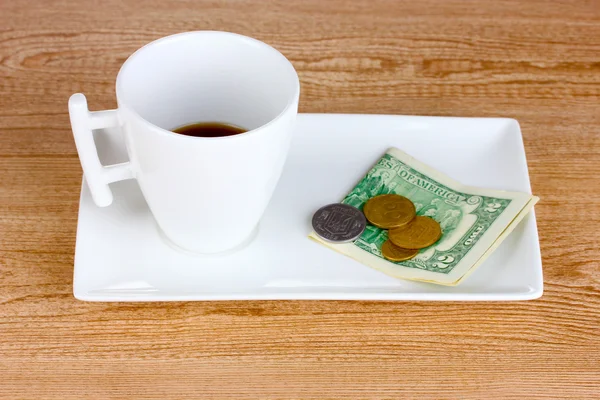 Taza vacía de café con cinco dólares de propina sobre fondo de madera . — Foto de Stock