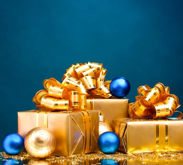 Vackra gåvor i guld förpackningar och christmas bollar på blå ba — Stockfoto