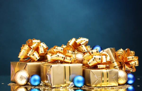 Красивые подарки в золотой упаковке и рождественские шары на голубой ба — стоковое фото