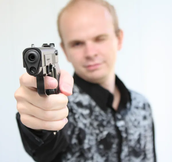 Mladý muž s pistolí v ruce zaměřené — Stock fotografie