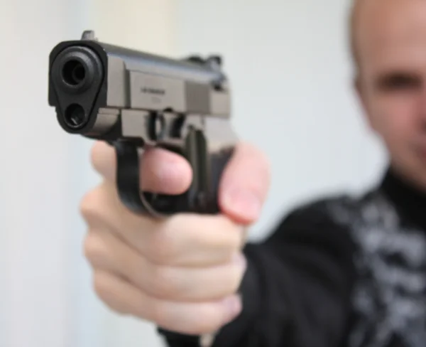 Mladý muž s pistolí v ruce zaměřené — Stock fotografie