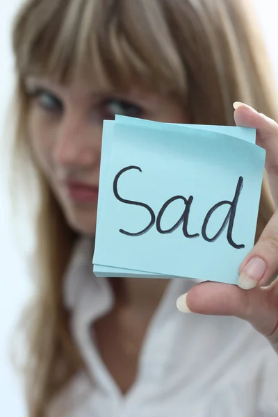Sad girl with note pad on white background — Stock Photo, Image