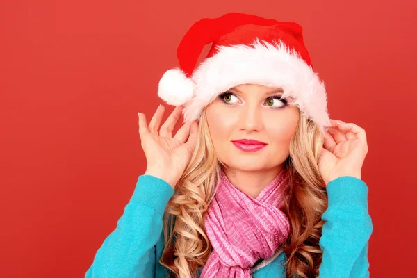 Beautiful christmas woman thinking in santa hat on red backgroun — Stock Photo, Image