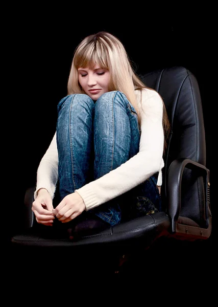 Молода дівчина з закритими очима на стільці на чорному тлі — стокове фото