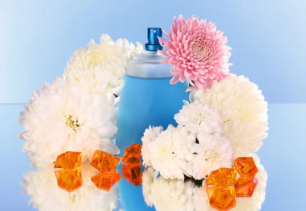 Frasco de perfume e flor no fundo azul — Fotografia de Stock