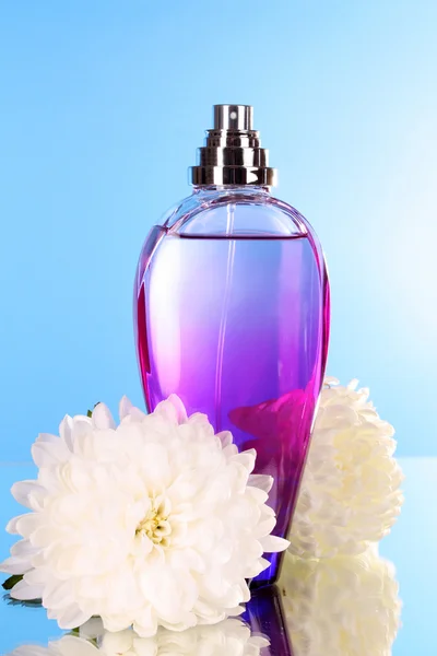 Бутылка духов и цветок на голубом фоне — стоковое фото