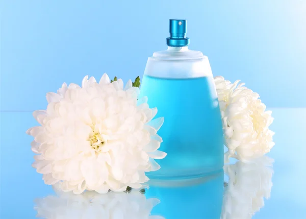 Perfum butelek i kwiat na niebieskim tle — Zdjęcie stockowe