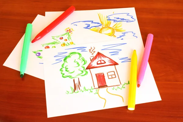 Детский рисунок и ручки на столе — стоковое фото