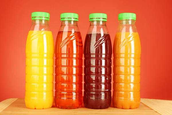 Bottles of juice on red background — Stock Photo, Image