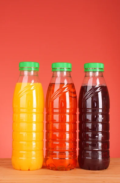 Flaschen Saft auf rotem Hintergrund — Stockfoto