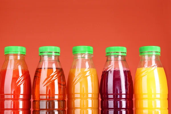 Butelek sok z dojrzałych owoców na czerwonym tle — Zdjęcie stockowe