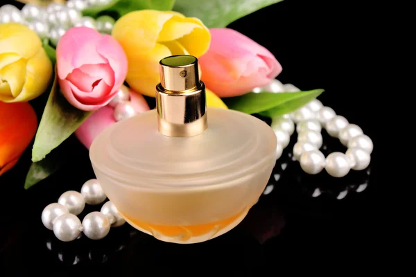 Brown bottle of parfume, tulips and pearls on black — Stock Photo, Image