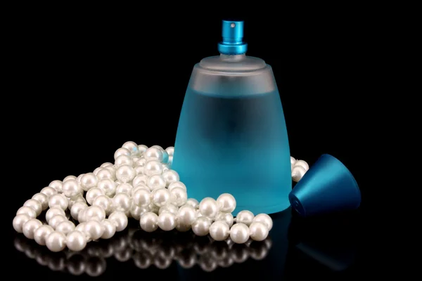 Синя пляшка парфумів і перлин на чорному — стокове фото