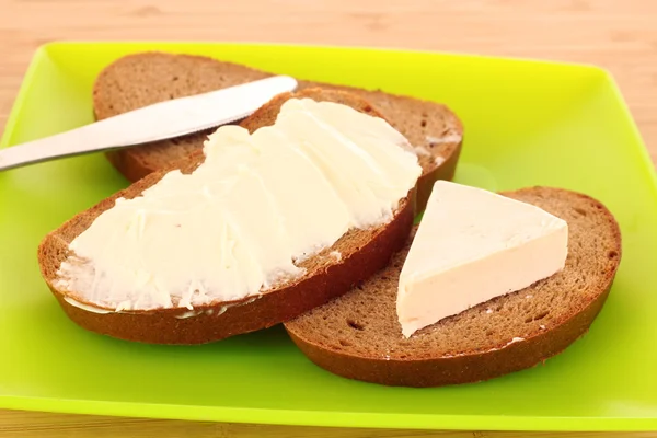 Faca e um pão com manteiga no prato — Fotografia de Stock