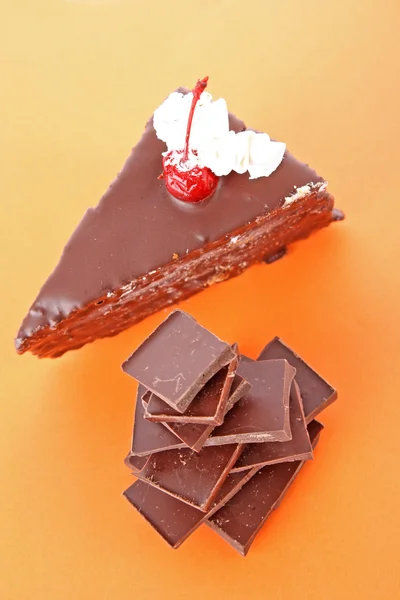 Piezas de chocolate negro, sobre fondo naranja — Foto de Stock