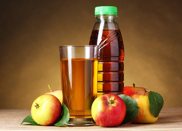 Apfelsaft und Äpfel auf Holztisch auf braunem Hintergrund — Stockfoto