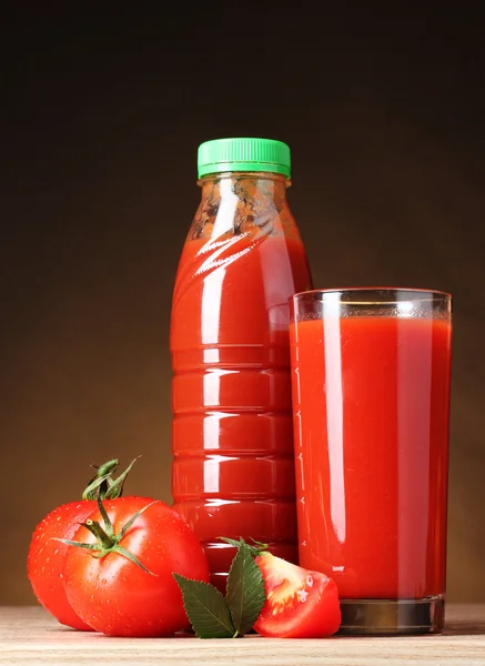 Tomatensaft im Glas und Tomaten auf Holztisch auf braunem Backgr — Stockfoto