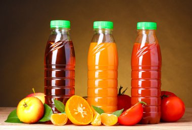 Different juices and fruits on wooden table on brown background clipart