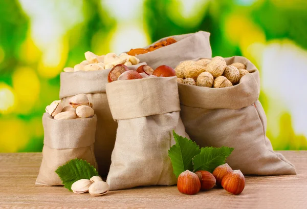 Many nuts in bags on green background — Stock Photo, Image