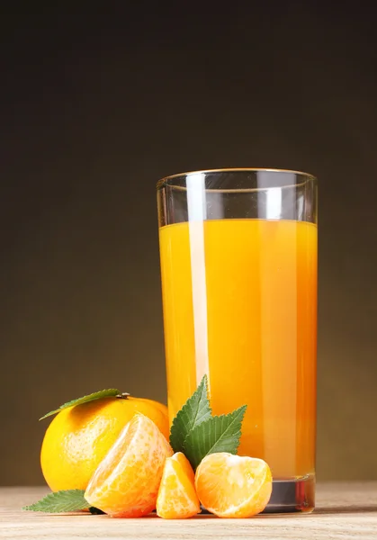 Tangeriner och juice glas på träbord på brun bakgrund — Stockfoto