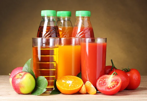 褐色背景的木制桌子上的不同果汁和水果 — 图库照片