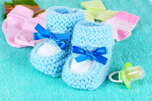 Botines de bebé azules, calcetines y chupete sobre fondo azul —  Fotos de Stock
